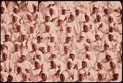 A large number of black women, wearing white hats and white tops with long sleeves.