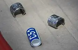Image showing bird leg rings, one blue with a white code C51 and two metal rings with unique codes placed on cardboard.