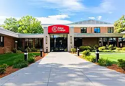 A landscaped area with a sidewalk leading to a brick building with a red awning