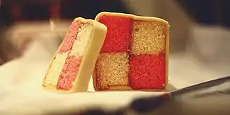 Battenberg cake covered in marzipan displaying a distinctive two-by-two check pattern in its cross-section