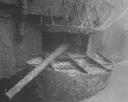 Underwater photograph of a gun protruding from an opening in the side of a sunken ship.