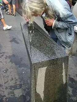 person bent over stone pillar with water