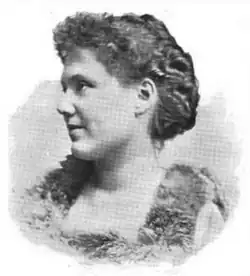 19th-century B&W portrait photo of a woman with her hair in an up-do, wearing a frilly top.