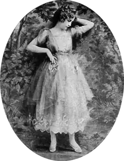 Black and white film still showing a woman in a layered, lace-trimmed dress