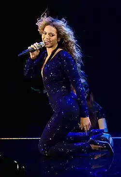 Beyoncé dressed in a sparkling bodysuit kneeling