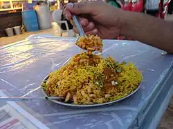 Bhel puri being eaten with a spoon on an outdoor table.