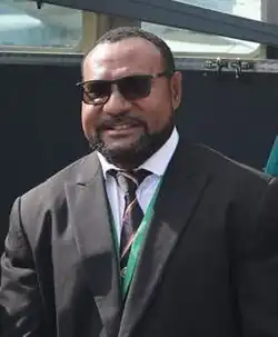 Headshot of Joseph wearing a suit and sunglasses