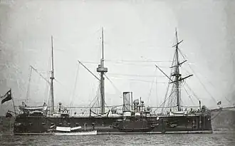 A three-masted black and white ship at port.