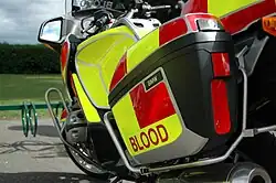 Container on the side of a bike with the word "blood" in red text on a yellow background