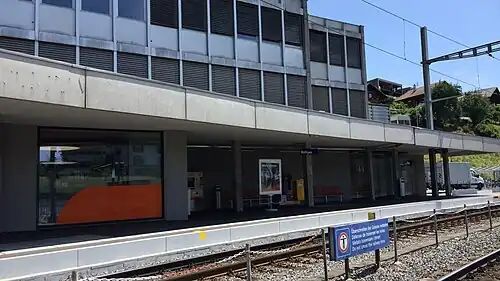 Single-story building with flat roof next to double track