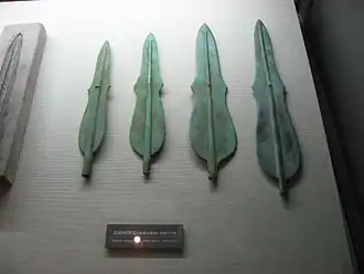 A set of four green bronze daggers in a museum display