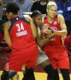 Thomas and Delle Donne wearing bright red uniforms attempt to squeeze Brunson out as she emerges between them