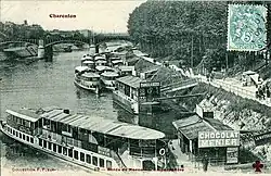 A black and white photograph of a quayside, showing several boats with passengers boarding and disembarking.