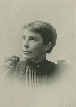 19th-century B&W portrait photo of a woman with her hair in an up-do, wearing a dark, fitted blouse.