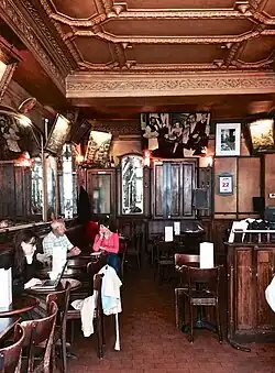 Café interior with ornate ceiling and patrons at small tables