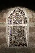 One of the windows of coloured glass set into a stucco grille
