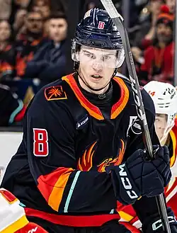 Ice hockey player in a Coachella Valley Firebirds jersey holding his stick up