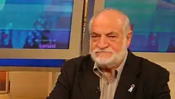 A bald man in formal wear with a white beard
