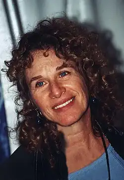 Carol King looking at the camera and smiling, wearing a blue top