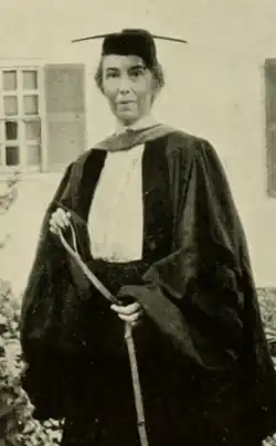 A white woman of middle age, wearing academic cap and gown