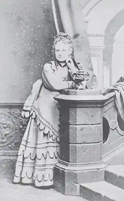 A young woman in a dress leaning against a bannister
