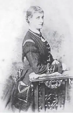 Side profile of a woman in a dress with her hands resting on a table