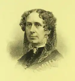 19th-century B&W portrait photo of a woman with her hair in an up-do, wearing a dark, fitted blouse.