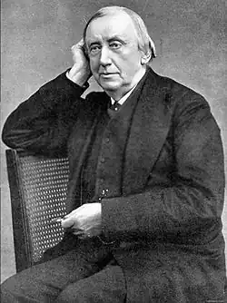 Middle-aged clean-shaven white man seated and leaning his head on one hand