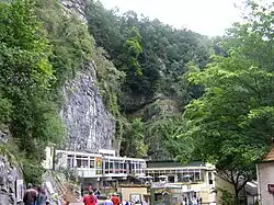 Exposed limestone cliffs with vegetation above white buildings with large windows.
