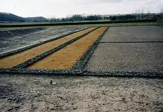 Color photograph of the base of long parallel walls.