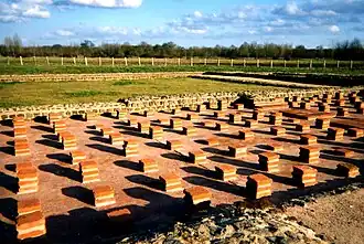 Color photograph of modern stacks of terracotta bricks reconstructing the same ancient system.