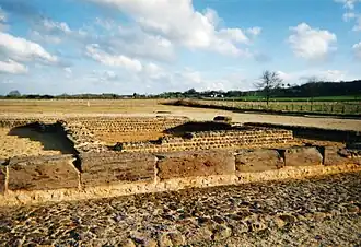 Color photograph of the base of two walls, one behind the other, the first in large blocks, the other in small rubble.