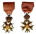 Late Empire Légionnaire insignia: the front features Napoleon's profile and the rear, the imperial Eagle. An imperial crown joins the cross and the ribbon.