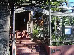 Brick steps lead up to the entrance of Chez Panisse, framed by a wooden archway and greenery