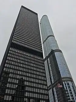 The facades of the IBM Building, a dark rectangular glass-and-aluminum structure, and the Trump Tower, a round glassy structure with several setbacks