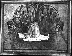 A nude, decapitated Chhinnamasta holds her severed head in her right hand and a sword in the left. She seats squatting on and in coitus with a white-complexioned naked Shiva lying on the ground. Cremation pyres appear in the background. Dogs and jackals feast on severed human heads in the foreground.