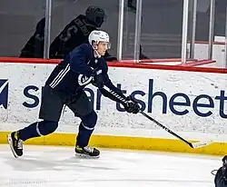 Ice hockey player in a Seattle Kraken jersey skating with his stick out