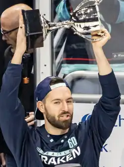 Man in a Seattle Kraken shirt holding up a trophy