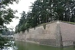 Photo shows a sloped wall next to a moat.