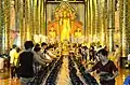 Inside the wihan of Wat Chedi Luang, money offerings are dropped into alms bowls during the festival