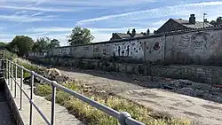 The existing remains of the station platform, now adjacent to a Tesco car park. Photo taken July 2025.