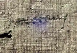 A close-up of of the disputed "γινέσθωι" subscription written on a fibrous, light-brown papyrus surface