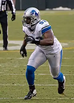 Cliff Avril in a full Detroit Lions uniform and helmet running.
