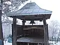 A fixed wooden semantron beneath bells at Căpuşneni church, Romania