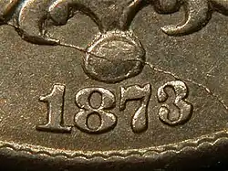 A closeup of part of an 1873 Shield nickel, showing the date, in which the arms of the "3" reach close to each other