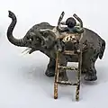 A black boy climbing up an elephant with a ladder. This one is just a bit different from the lost figurine (NF.1914-0491).