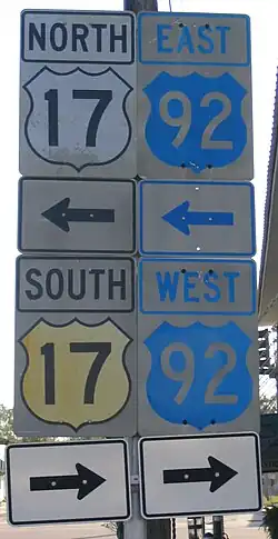 Four U.S. Route signs, two for US 17 and two for US 92. The US 17 signs have yellow shields with black text, while the US 92 signs have blue shields with white text.