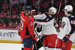 Ice hockey player in a Columbus Blue Jackets jersey putting his hands on an ice hockey player in a Washington Capitals jersey