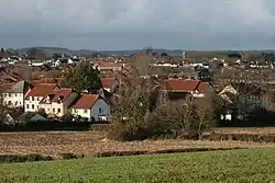 Multiple reddish brown roofs of houses. A church tower is visible in the distance.
