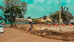 the outside of a brown building and a field with people walking in front